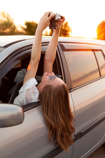 Side view of woman taking a selfie with camera while in the car