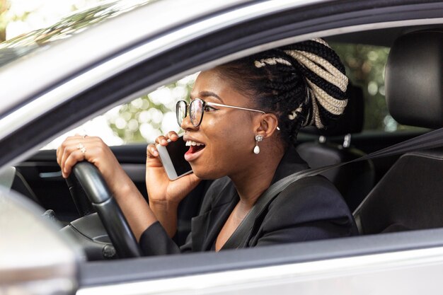 그녀의 차를 운전하는 동안 스마트 폰에 얘기하는 여자의 모습