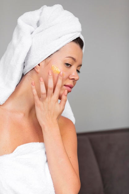 Side view of woman in towel using skincare