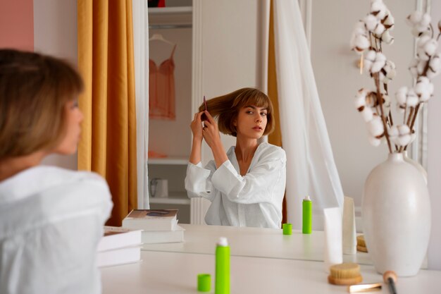 Free photo side view woman using dry shampoo at home