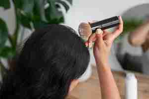 Free photo side view woman using dry shampoo at home