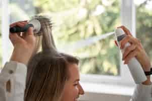 Free photo side view woman using dry shampoo at home