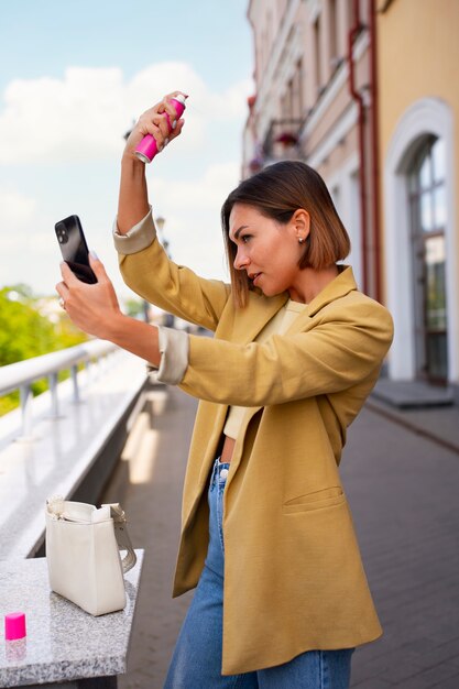 Side view woman using dry shampoo outdoors