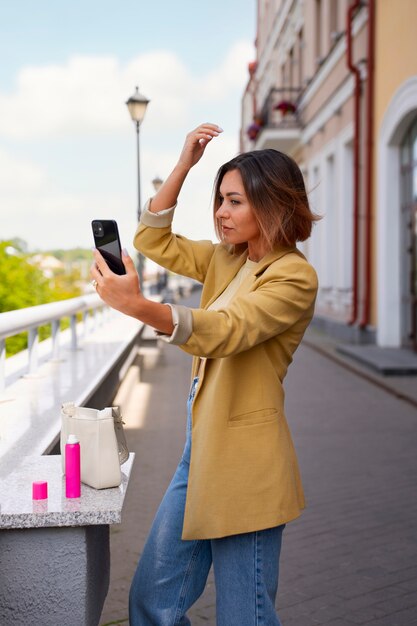 Side view woman using dry shampoo outdoors