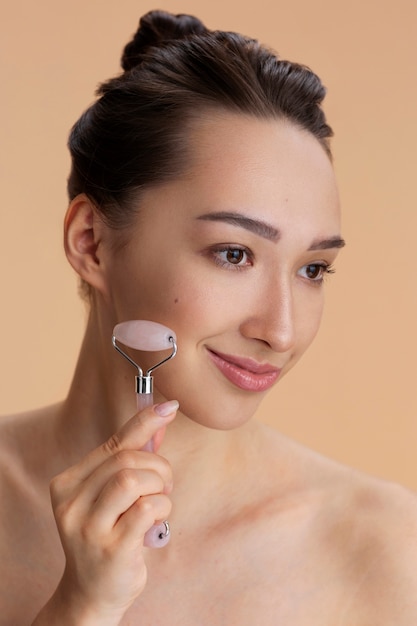 Free photo side view woman using face roller