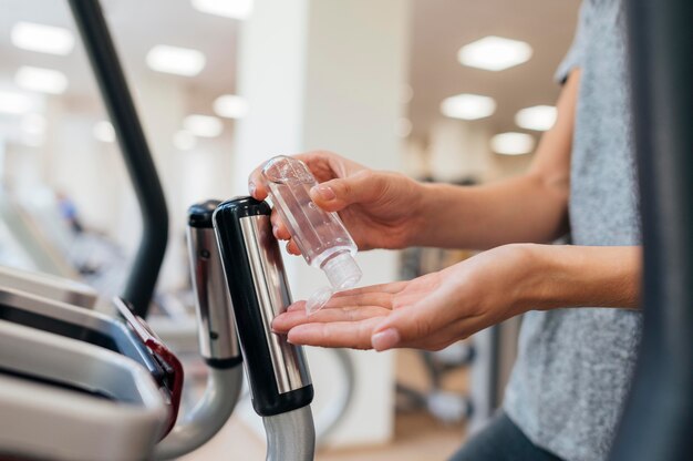 Side view of woman using hand sanitizer at the gym during pandemic