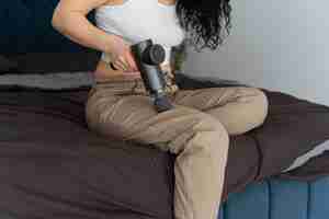 Free photo side view woman using massage gun