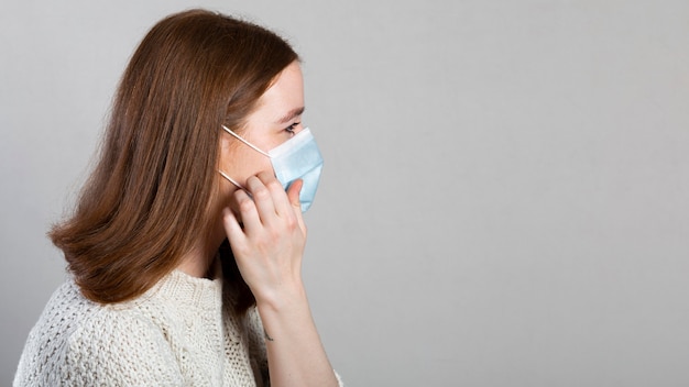 Foto gratuita vista laterale della donna che utilizza una mascherina medica per la protezione con lo spazio della copia