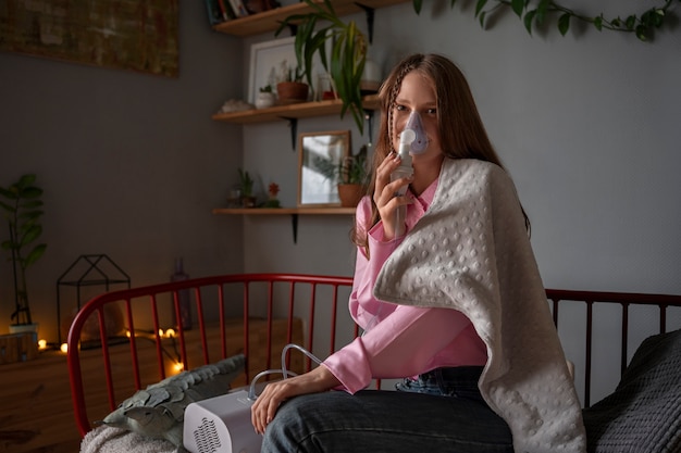 Free photo side view woman using nebulizer at home