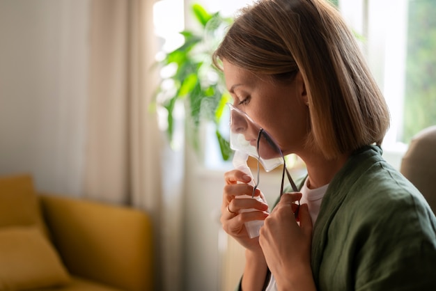 Foto gratuita donna di vista laterale che utilizza il nebulizzatore