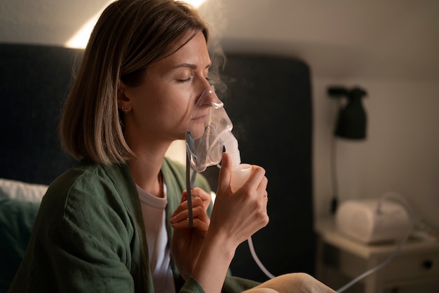 Free photo side view woman using nebulizer