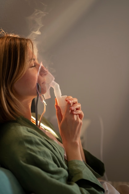 Foto gratuita donna di vista laterale che utilizza il nebulizzatore