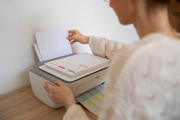 Free photo side view woman using printer at office