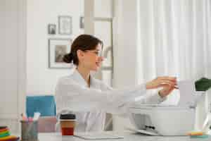 Free photo side view woman using printer at work