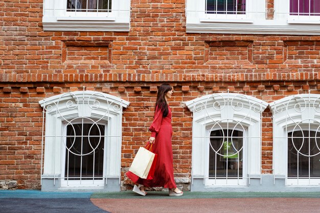 Side view of woman walking on the street with shopping bags