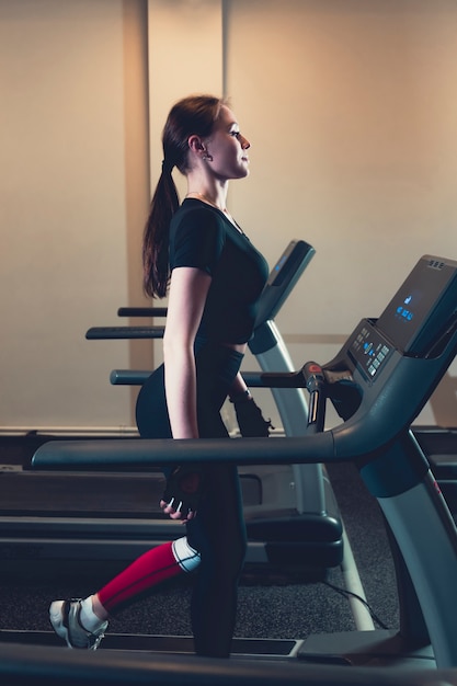 Side view of woman walking on treadmill at gym