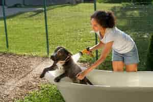 Free photo side view woman washing dog in bathtub