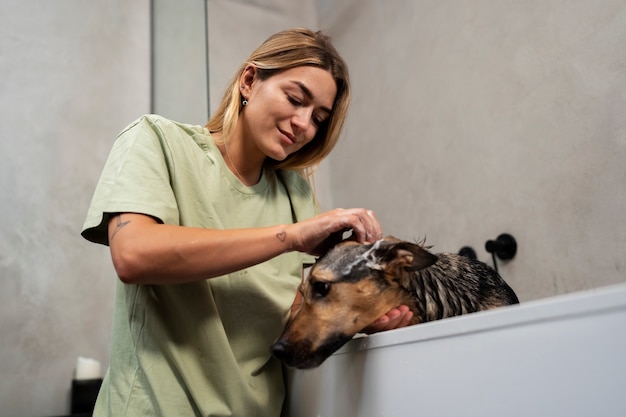 Free photo side view woman washing dog