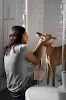 Free photo side view woman washing dog