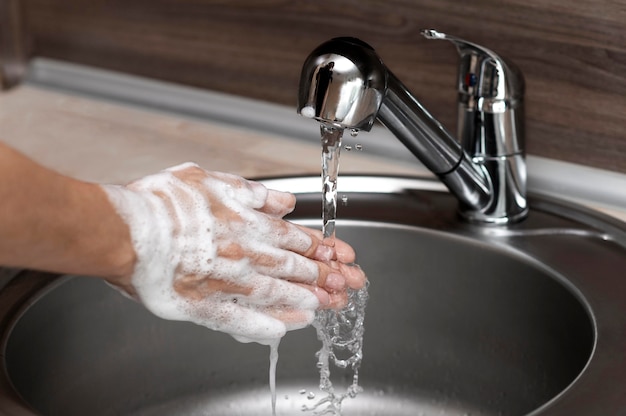 Free photo side view woman washing hands in a sink