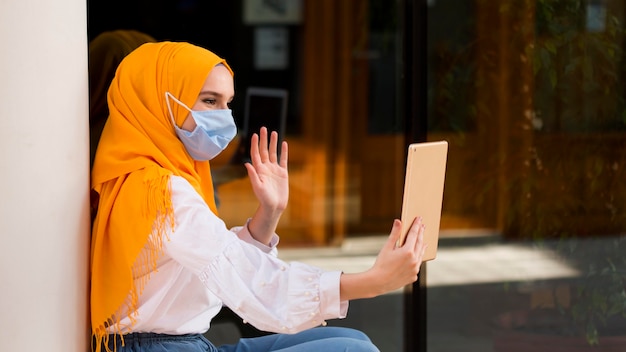 Side view woman waving at tablet