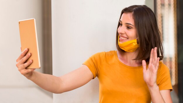 Side view woman waving at tablet