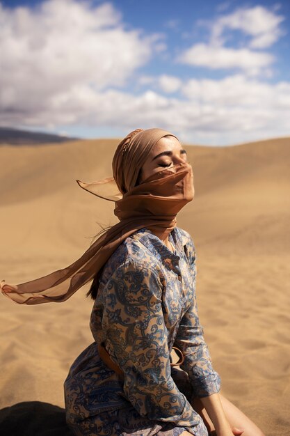 砂漠でスカーフを身に着けている側面図の女性