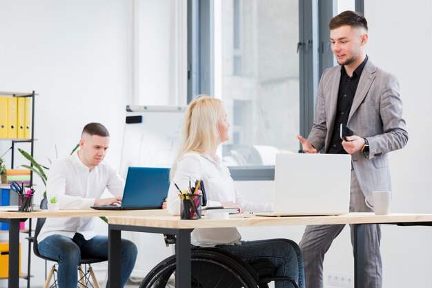 Side view of woman in wheelchair conversing with male coworker