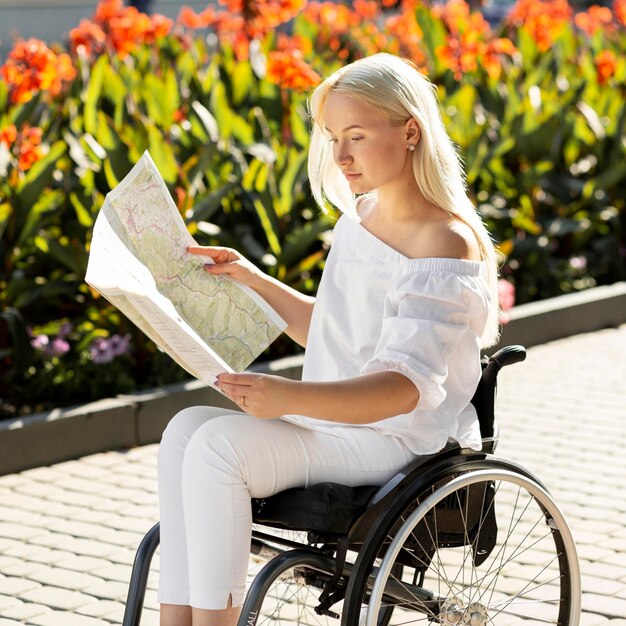 Side view of woman in wheelchair looking at map outdoors