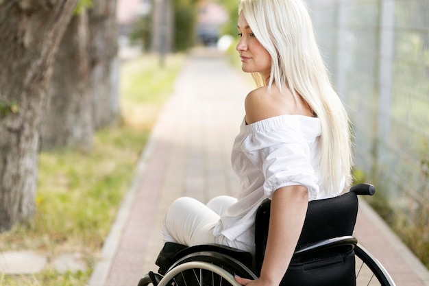 Side view of woman in wheelchair outdoors with copy space