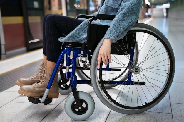 Donna di vista laterale in sedia a rotelle alla stazione della metropolitana