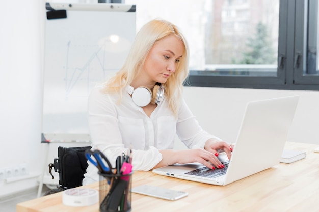 Free photo side view of woman in wheelchair working on laptop