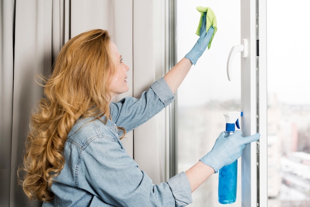 Side view of woman wiping window