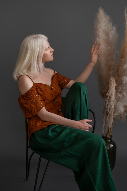 Free photo side view woman with albinism posing in studio