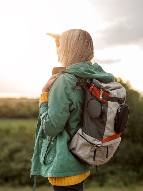 Foto gratuita donna di vista laterale con lo zaino al tramonto