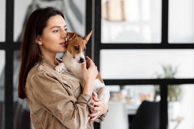 腕の中でかわいい犬を持つ女性の側面図