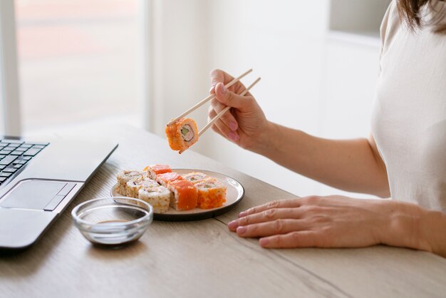 Free photo side view woman with delicious sushi at home