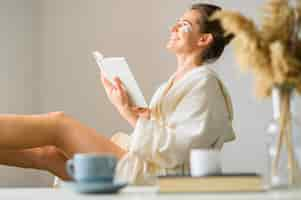 Free photo side view of woman with eye patches reading a book