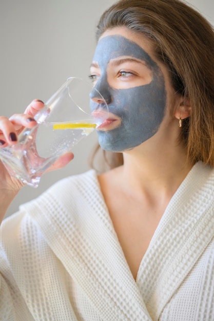 Foto gratuita vista laterale della donna con l'acqua potabile della maschera di protezione con il limone