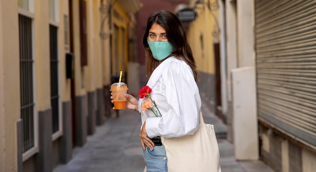 フェイスマスクと食料品の袋を持つ女性の側面図