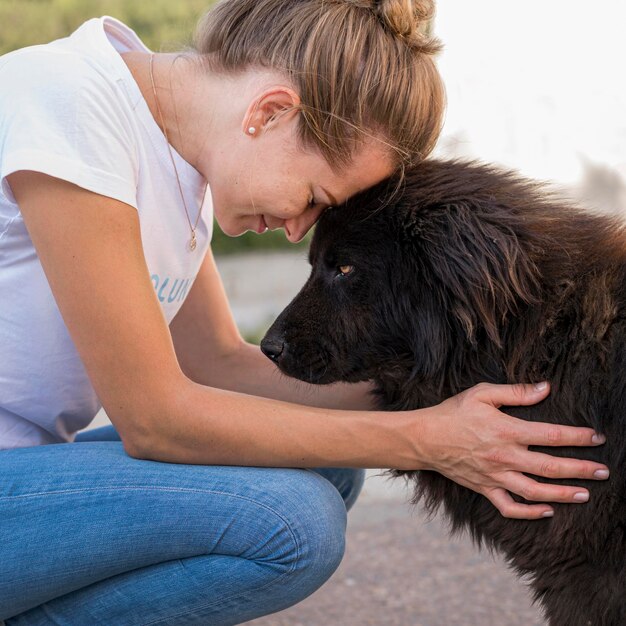 Side view of woman with fluffy black dog outdoors