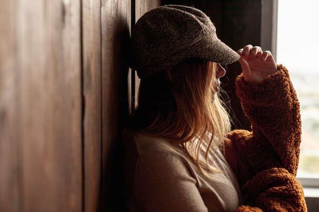 Side view woman with hat posing indoors