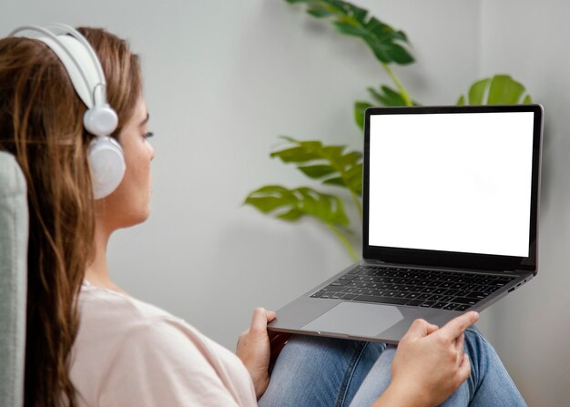 Вид сбоку женщина с наушниками, используя ноутбук