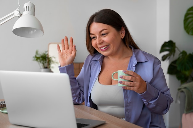 Foto gratuita donna di vista laterale con il computer portatile a casa