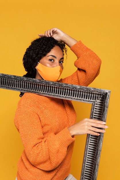 Side view of woman with mask holding frame