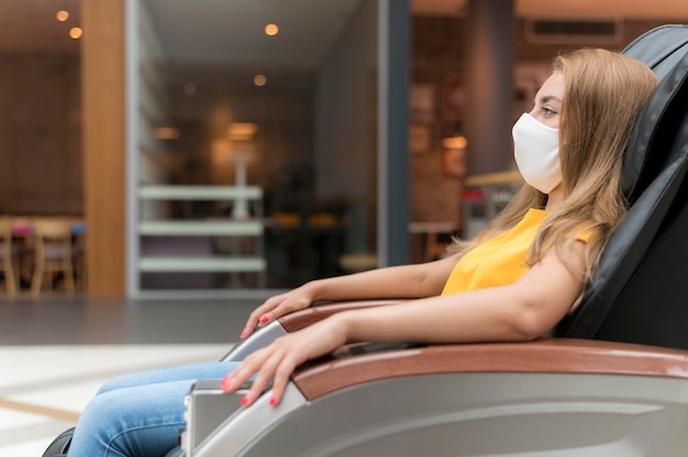 Side view woman with mask on massage chair