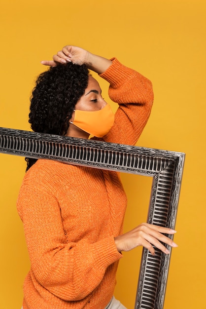 Side view of woman with mask posing with frame