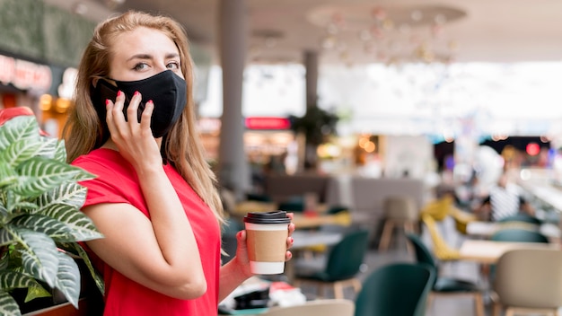 Donna di vista laterale con la maschera che parla sul cellulare