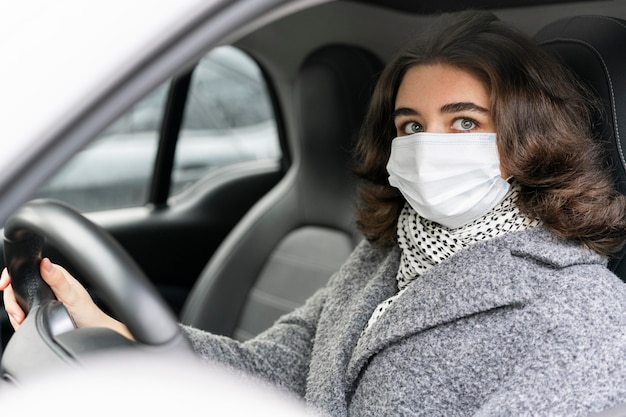 車を運転する医療マスクを持つ女性の側面図