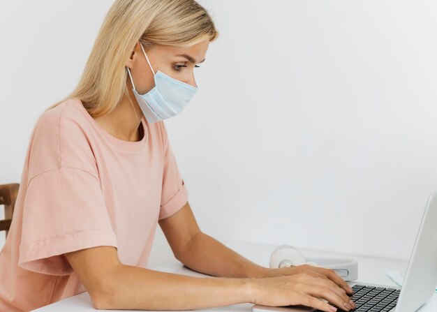 Side view of woman with medical mask working from home during the pandemic